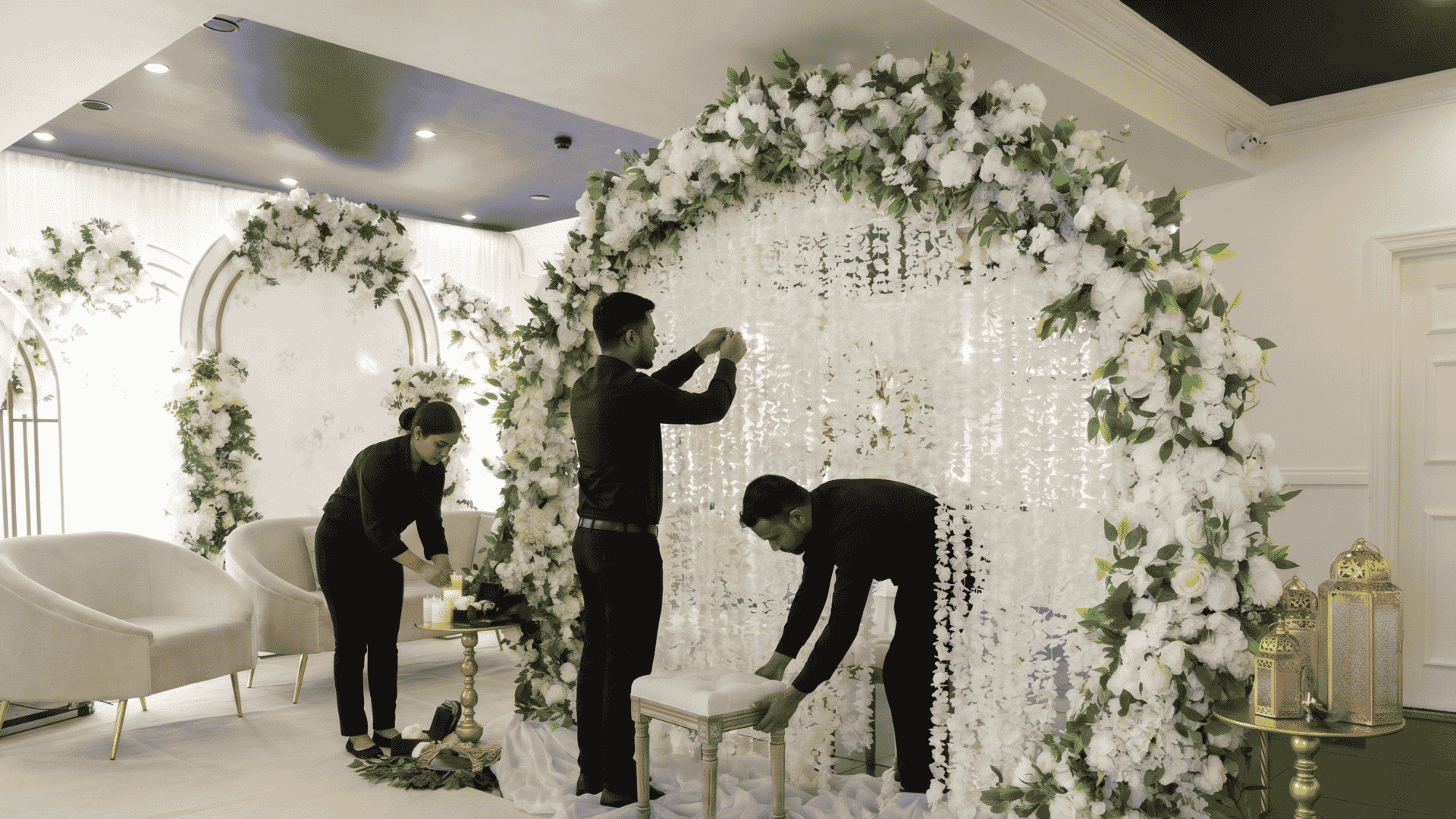 Wedding planning setup in a dry hire venue with decorated tables, floral centrepieces, ceremony aisle, and event suppliers preparing the hall